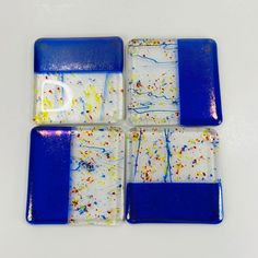 four blue and white square coasters with sprinkles on the top, one is