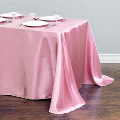 a pink table cloth with white plates on it