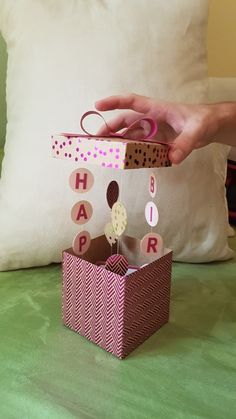 a person is holding a box with some decorations in it on a green surface next to a pillow