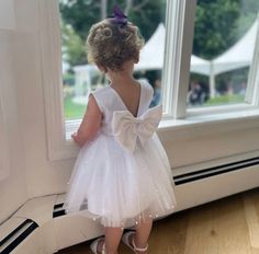 Our enchanting Knee Length flower girl dresses are sure to turn heads! This beautiful elegant sophisticated dress is handmade, the bodice consists of White Bridal Satin with a sowed in sash at the waist, the back of the dress consists of an open V-back with a hidden zipper. The big bow is detachable. The skirt consists of 4 white layers of tulle with the top layer consisting with sowed in pearl beads. The fifth layer is made of lining with crinoline for fullness.  This dress is perfect for any o Fitted Baptism Dress With Bow, Fitted Tutu Dress With Bow For Baptism, Fitted Tulle Baptism Dress With Bow, Fitted Princess Dress With Satin Bow For Baptism, Elegant Tutu Dress With Bow For Baptism, Fitted Tutu Dress With Bow For Wedding, First Communion Princess Dress With Satin Bow, Elegant Baptism Dress With Satin Bow For Pageant, Elegant Baptism Tutu Dress With Bow