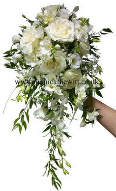 a bouquet of white flowers is being held by someone's hand