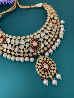 Gold plated uncut kundan necklace . Silver foil work and ruby red kundan work. The thickest part of the necklace is two and half inch wide . Pendent is 2 inch long . comes with matching earring. About 3 inch long . Kundan box -1 Traditional Ruby Kundan Necklace With Meenakari, Traditional Ruby Meenakari Kundan Necklace, Ruby Chandbali Kundan Necklace With Intricate Design, Festive Ruby Kundan Necklace With Cutdana, Bollywood Style Ruby Kundan Necklace, Hand Set Chandbali Kundan Necklace, Red Kundan Necklace With Stone Work, Heavy Ruby Chandbali Kundan Necklace, Ruby Kundan Necklace With Intricate Design For Diwali