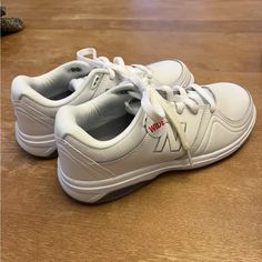 a pair of white shoes sitting on top of a wooden floor