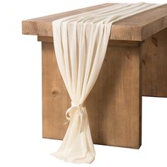 a wooden bench with a white curtain hanging from it's side and an attached seat