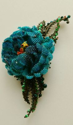 a beaded brooch with a blue flower on it