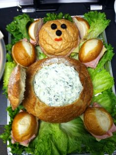 a tray with bread, meat and vegetables on it that has a teddy bear in the center