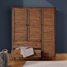 a wooden armoire sitting on top of a hard wood floor next to a rug