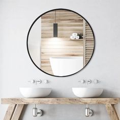 a bathroom with two sinks and a round mirror on the wall above it's counter