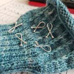 two pairs of silver earwires sitting on top of a blue knitted bag