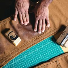 a person with their hands on a piece of paper next to some scissors and tape