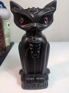 a black cat figurine sitting on top of a table next to other items