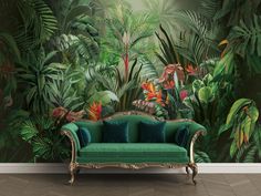 a green couch sitting in front of a wall with tropical plants and flowers on it