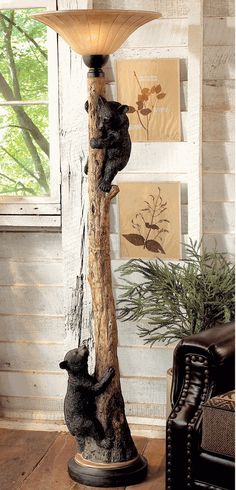 two bears are climbing up the side of a tree trunk lamp with a shade on it