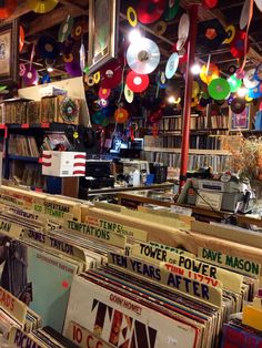 an old record store with lots of records on the shelves and lights hanging from the ceiling