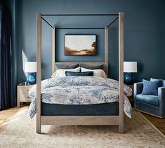 a bed room with a neatly made bed and two blue chairs in front of it