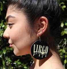 a woman wearing earrings with the word virgo painted on it