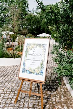 an easel with a welcome sign on it in front of some bushes and trees