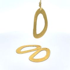 a pair of gold earrings sitting on top of a white table