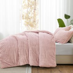 a bed with pink comforter and pillows on it