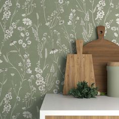 a cutting board sitting on top of a counter next to a wallpapered wall