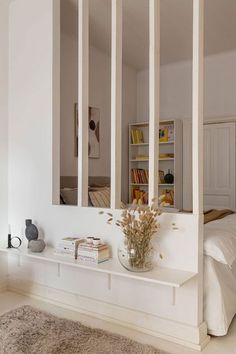 a bedroom with white walls and flooring has a large mirror on the wall above the bed