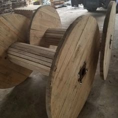 three wooden spools sitting next to each other on top of a table in a warehouse