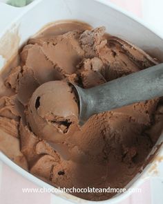 a scoop of chocolate ice cream in a white bowl with a metal spatula on top