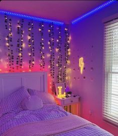 a bed room with a neatly made bed next to a night stand and window covered in lights