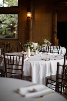 the table is set with white linens and floral centerpieces for an elegant wedding reception