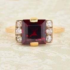 A stunning art deco 18ct gold garnet & diamond dress ring. A wonderous central deep red rhodolite garnet is set neatly within this very stylish ring. It is flanked either side by a trio of warm and deep bright white old cut diamonds which compliment it perfectly. The clean geometric design oozes with character and is typical of the art deco period. A part of our art deco ring collection. SIZE UK O / US 7 - Free sizing available  SPECIFICATION Garnet carat weight approx. 2.7 carat Diamonds total Formal Art Deco Ruby Ring In Yellow Gold, Art Deco Yellow Gold Ruby Ring For Formal Events, Formal Garnet Burgundy Ring, Formal Burgundy Garnet Ring, Red Brilliant Cut Diamond Ring In Art Deco Style, Art Deco Ruby Ring With Diamond Details, Art Deco Yellow Gold Ruby Ring, Vintage Garnet Ring With Center Stone, Formal Princess Cut Ruby Ring With Center Stone