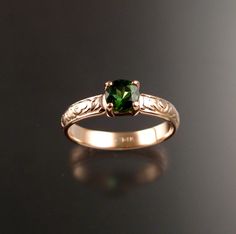 a gold ring with a green stone in the center