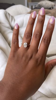 a woman's hand with pink nail polish and a diamond ring on her finger