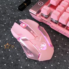 a pink computer mouse sitting on top of a black carpet next to a keyboard and mouse pad