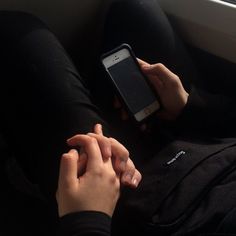 a person sitting on a couch holding a cell phone in their hand and looking at the screen