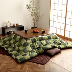 a living room filled with furniture next to a wooden table and floor covered in pillows