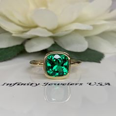 This ring is a cushion cut lab created green emerald bezel set solitaire, 14k yellow gold #6370 We feature the finest quality lab grown emeralds in the world. The properties of lab-grown are physically, chemically and visually identical to natural, just grown in a lab setting. Emerald is the birthstone of May -Approximate total carat weight: 2.40ctw diamond equivalent -Center Stone Size: approx. 2.40ct diamond equivalent -Center Stone Shape: cushion cut 8x8mm -Gem Type: lab created emerald -Ston Fine Jewelry Emerald Ring In Cushion Cut Yellow Gold, Fine Jewelry Yellow Gold Cushion Cut Emerald Ring, Cushion Cut Emerald Green Rings, Cushion Cut Emerald Ring In Yellow Gold, Yellow Gold Cushion Cut Emerald Ring Gift, Cushion Cut Emerald Green Jewelry, Cushion Cut Yellow Gold Emerald Ring As Gift, Green Cushion Cut Halo Setting Jewelry, Green Cushion Cut Jewelry With Halo Setting