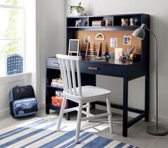 a desk and chair in a room with a blue rug on the floor next to a window