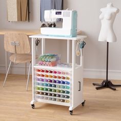 a sewing machine sitting on top of a wooden table next to a white shelf filled with craft supplies