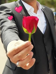 a man in a tuxedo holding a rose with hearts on its lapel