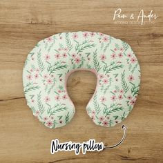 the nursing pillow has pink flowers on it and is sitting on a wooden surface with text reading nursing pillow