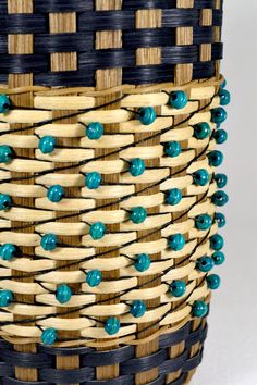 a close up of a basket with blue beads on it's sides and wood handles