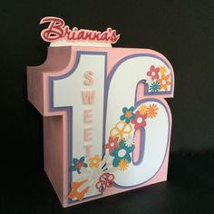 a pink and white birthday card with flowers on the number six, in front of a black background