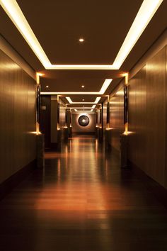 an empty long hallway with lights on either side and floor to ceiling lighting at the end