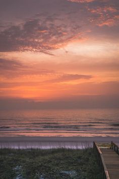 a wooden walkway leading to the beach at sunset