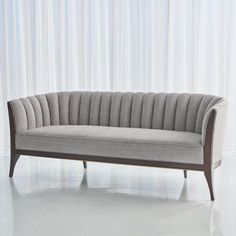 a gray couch sitting on top of a white floor next to a curtained wall