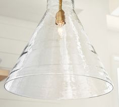 a glass light hanging from the ceiling in a room with white walls and wood flooring