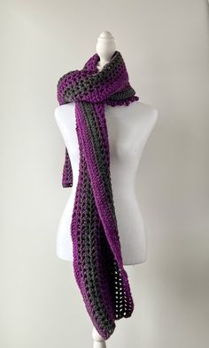 a white mannequin wearing a purple and black crochet scarf