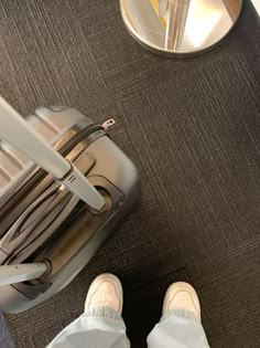 a person standing next to a piece of luggage on top of a carpeted floor