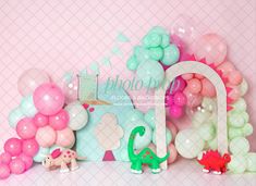 there are balloons and other decorations on the shelf in front of the wall, including an elephant balloon arch