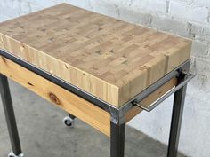 a wooden table sitting on top of a metal frame next to a white brick wall